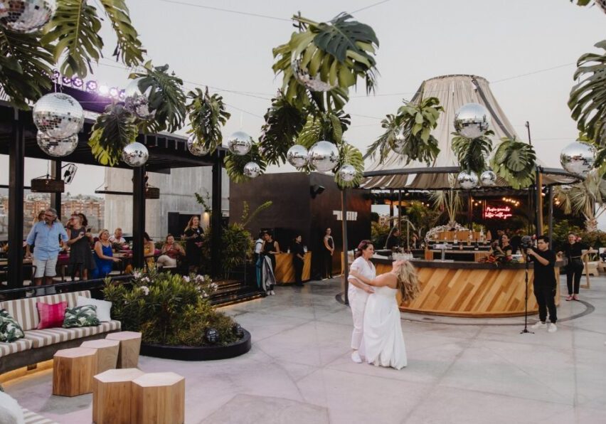 the brides dance under a stringed canopy of disco balls and palm fronds