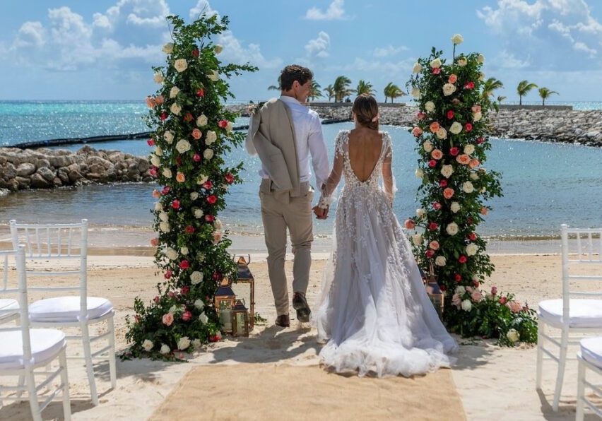 couple standing between two floral pillars